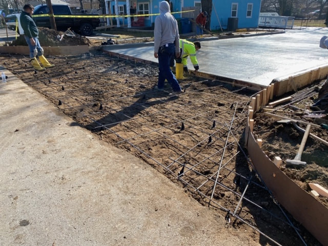 Workers pouring and leveling concrete driveway.