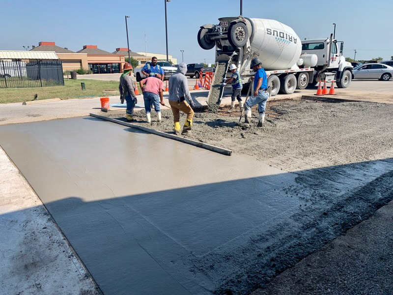 Team of concrete workers grading new pad